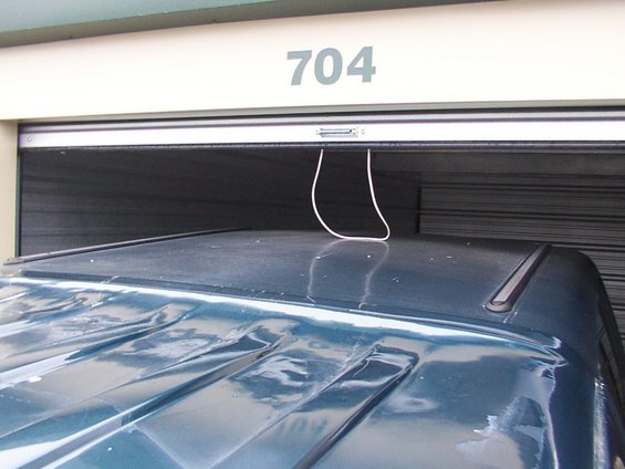 Dark blue SUV roof with visible creases, parked in front of a garage door labeled 704