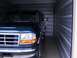 1988 Ford C-350 (Centurion Conversions) - This dark blue Ford F-Series truck is parked inside a storage unit.