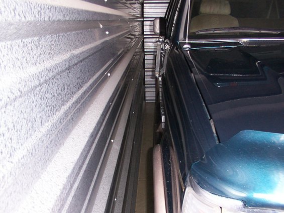 Dark green SUV parked tightly in a storage unit, showing the front passenger side and hood
