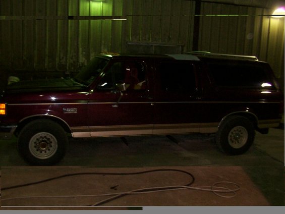 Maroon Ford Bronco with tan trim, seen from the side in a garage