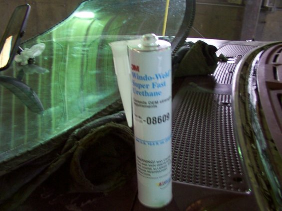 Tube of 3M Wind-Weld Super Fast Urethane sealant next to a vehicle windshield and dashboard