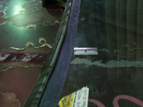 Close-up of a vehicle's windshield edge with peeling paint on the bodywork