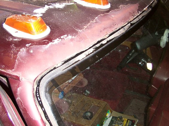 Maroon windshield frame and roof with peeling paint and amber marker lights