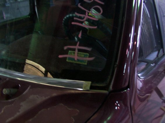 Windshield with pink writing and a sticker