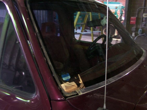 Interior view of a vehicle, showing the dashboard, steering wheel, and windshield. A blue sticker with the number 7122 is visible on the windshield