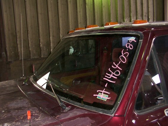 Maroon truck windshield with pink writing "#-1464-05-89" and stickers
