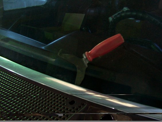 Red-handled windshield wiper removal tool on a vehicle dashboard
