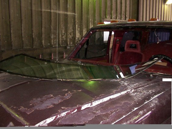 Truck hood with peeling paint and a cracked windshield. Interior is visible
