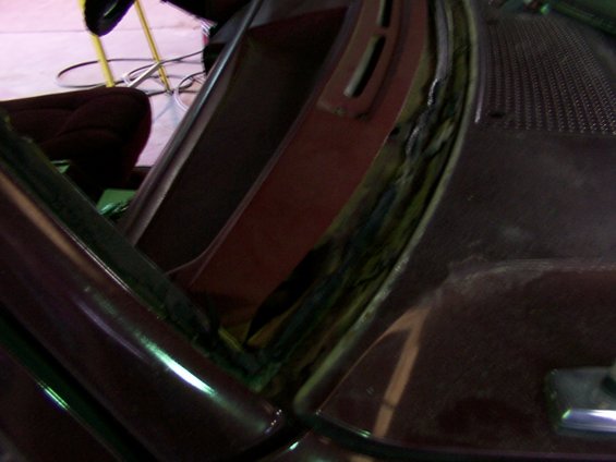 Damaged windshield seal on dark red vehicle interior