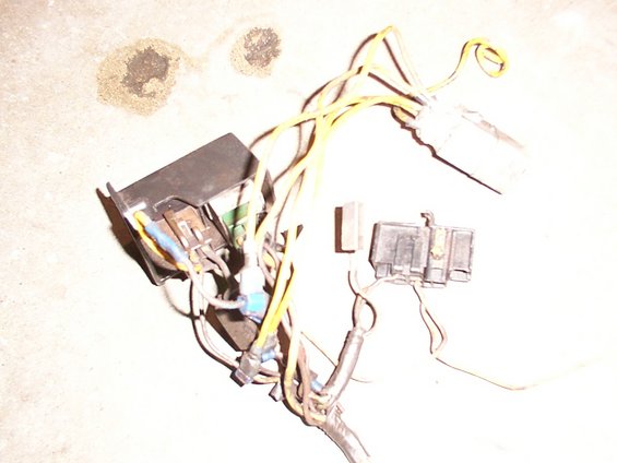 Vehicle wiring harness with multiple yellow wires and two black connectors. One connector is larger and has a black housing