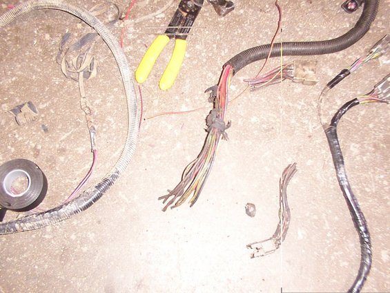 Wire cutters and a messy vehicle wiring harness on a concrete floor