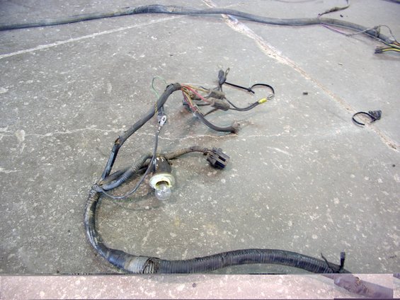 Automotive wiring harness with a light bulb socket and connectors, lying on a concrete floor
