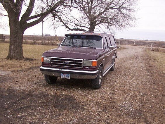 1987 Ford F-Series truck with camper shell parked on gravel driveway