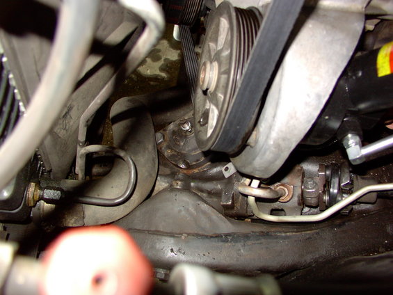 Close-up of engine pulleys, belts, and hoses