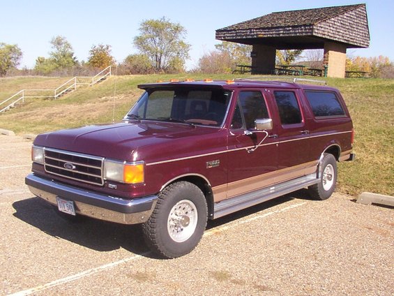 Maroon Ford truck with tan lower trim and chrome wheels, parked in a lot