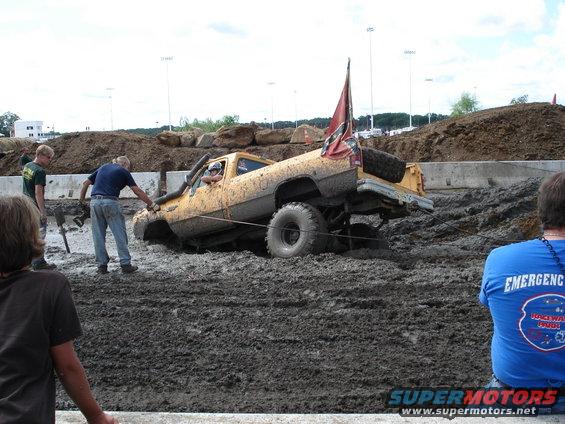 Yellow pickup truck stuck in mud, with a Confederate flag on the back