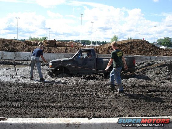 guy pulling a stuck pickup truck out of mud