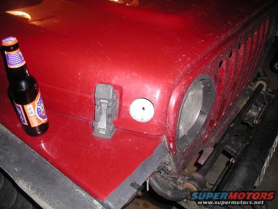 Red Jeep hood with a beer bottle and latch. Front view
