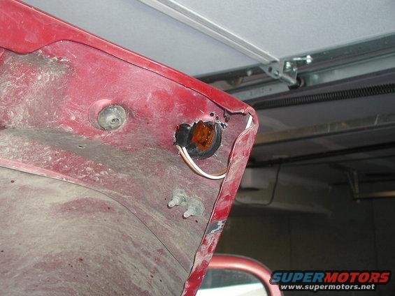 Red car hood interior with exposed orange turn signal housing and wiring