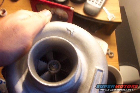 hand holding a turbocharger with a small chip on its housing