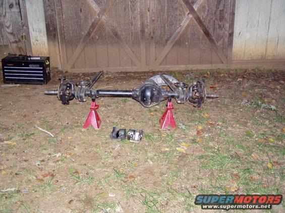 Front axle assembly on red jack stands, with toolbox nearby