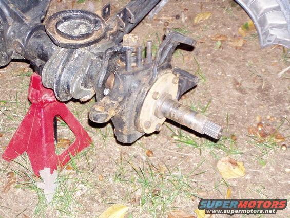 Front axle assembly on a red jack stand, with grass and dirt around it