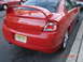 2005 Dodge SRT-4 - A red Dodge Neon sedan is parked on the street, showing its rear spoiler and dual exhaust pipes.