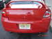 2005 Dodge SRT-4 - Rear view of a red Dodge Neon SRT-4 with a spoiler and dual exhaust pipes, parked outdoors.