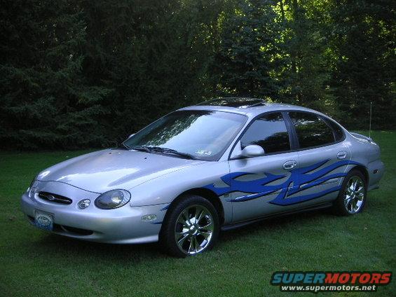 Silver 1999 Ford Taurus with blue flame decals and sunroof
