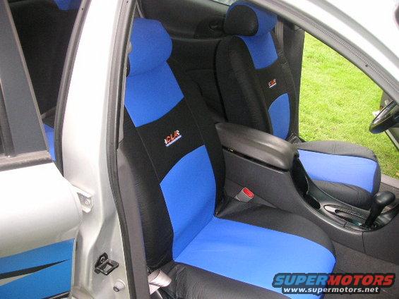 Car interior showing front seats with blue and black seat covers, center console, and door panel