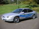 1999 Ford Taurus - A silver 1999 Ford Taurus sedan with custom blue flame decals and chrome wheels is shown from a three-quarter front angle.