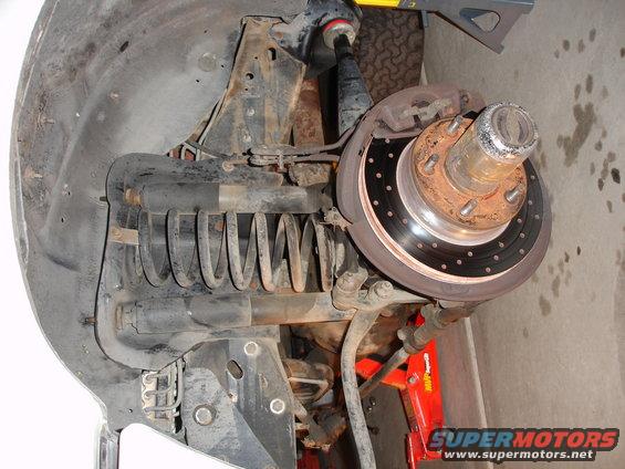 Front suspension part with coil spring and brake rotor. Supermotors.net logo visible