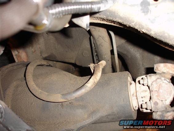 Close-up of a vehicle's rear axle and driveshaft components. Shows a hose and some suspension parts