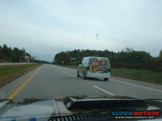 Van with a mural painted on the back, driving on a highway