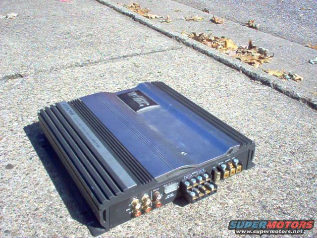Blue car amplifier with black fins and gold connectors on concrete