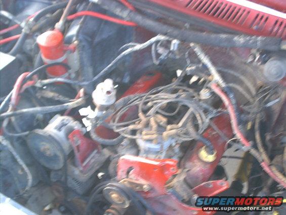 1986 Ford Bronco engine bay with red engine block, distributor, and alternator