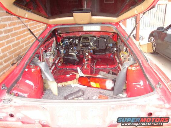 red car interior stripped down to the metal, showing wiring and components