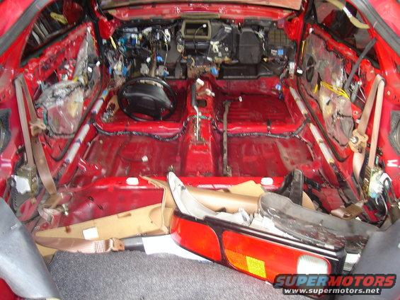 Red 1997 Ford Probe interior stripped bare, showing exposed wiring and body panels