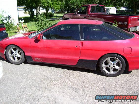 Red coupe with black trim, side view. Appears to be a 1993 Ford Probe