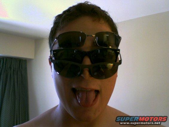 Person wearing three pairs of sunglasses stacked on their face, sticking out their tongue