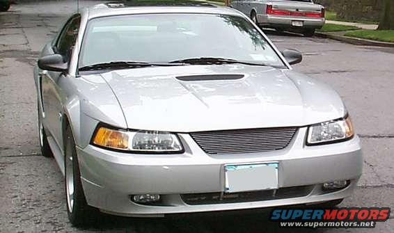 Front view of a silver 2000 Ford Mustang with a custom grille parked on a street