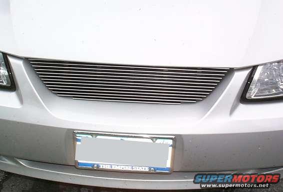 Silver car front with horizontal chrome grille and license plate frame reading "THE EMPIRE STATE"