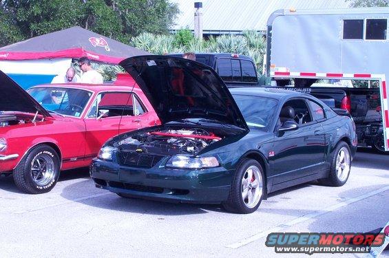 Dark green coupe with hood open, showing engine bay. Visible side badge indicates a GT model
