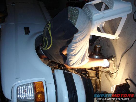 1996 Ford Bronco front suspension work, person bent over engine bay
