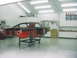 1990 Ford Mustang - Car body on a rolling stand in a well-lit garage, undergoing restoration.