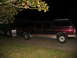 1988 Ford C-350 (Centurion Conversions) - A custom extended Ford Bronco SUV is towed by a semi-truck at night.