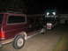 1988 Ford C-350 (Centurion Conversions) - Maroon Ford Bronco SUV and a green semi-truck are parked side-by-side in a driveway at night.