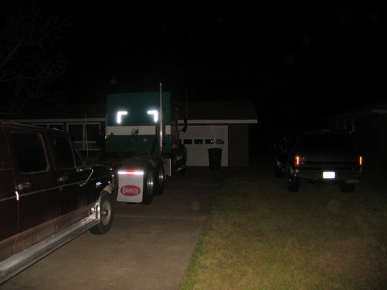 Semi-truck and pickup truck parked in a driveway at night