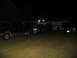 1988 Ford C-350 (Centurion Conversions) - A black Ford Bronco is parked next to a semi-truck and another SUV in a driveway at night.