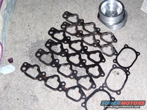 Engine gaskets and a metal adapter on a carpeted surface
